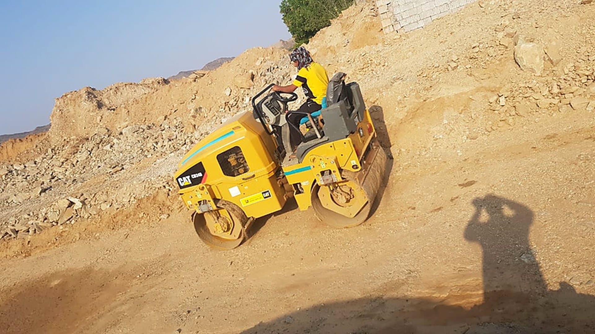 مدحلة تعمل على دمك مسار ترابي في موقع تنفيذ